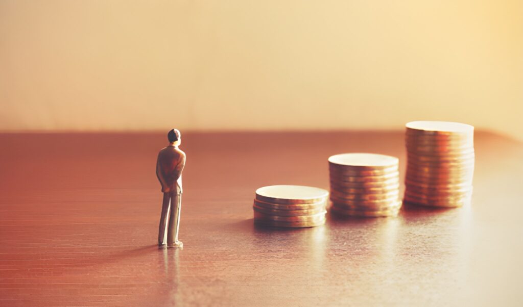 A miniature figurine of a man looking toward three gold coins