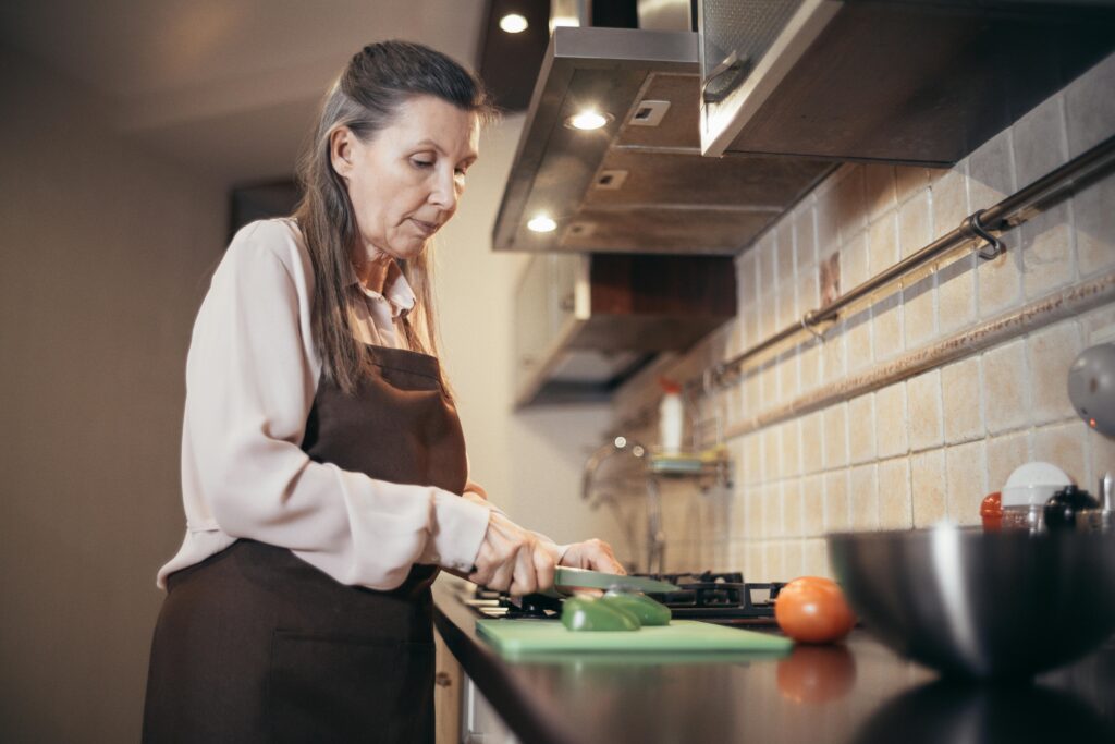 A middle-aged woman slicing a green bell pepper
