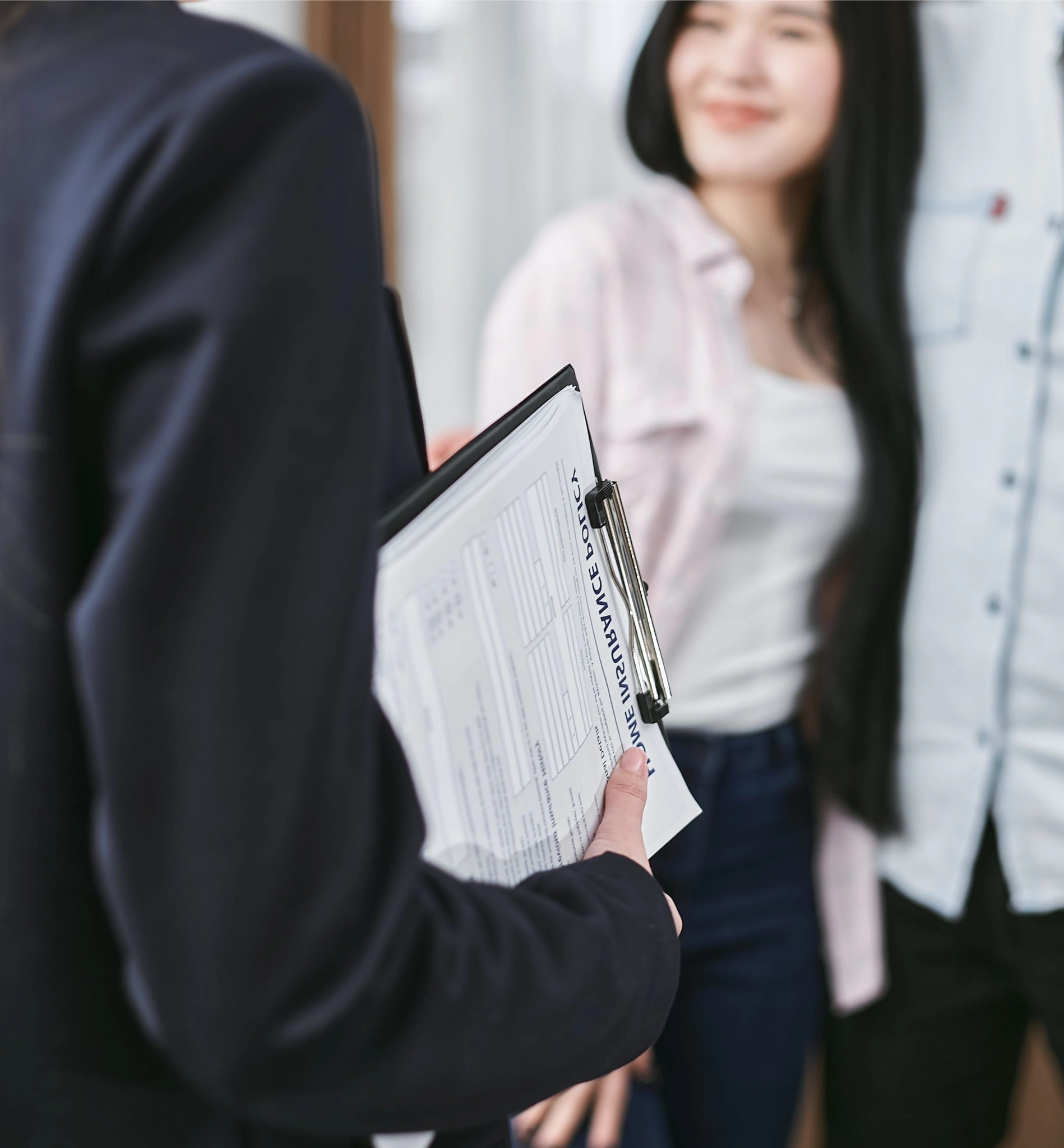 insurance agent holding a home insurance policy clipboard while consulting a smiling young couple